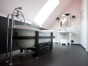 Klasyczna łazienka w kolorze chłodnego różu i bieli z czarną podłogą.